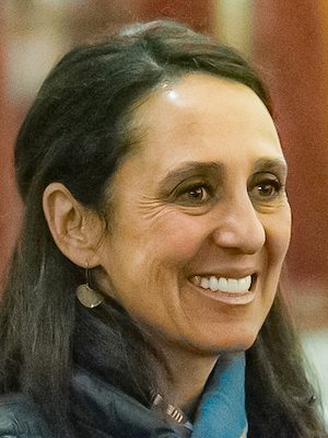 Maria Estrada, a Latinx woman with long brown hair smiling.