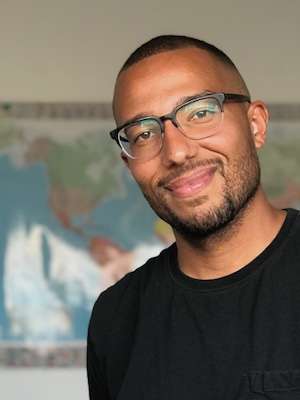An African-American man with close cropped hair and glasses smiling.